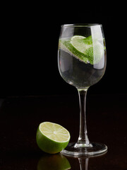 a glass of fresh drinking water and lime. mineral water as a means to quench thirst. on a black background.