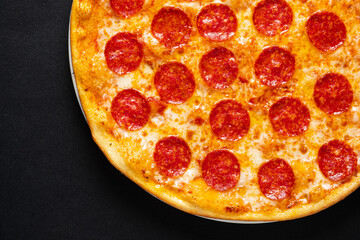 Tasty pepperoni and tomatoes on black background
