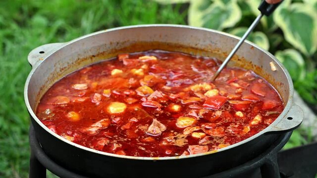 Hungarian traditional bograch. Making stew on open fire. german comfort food. Traditional Hungarian Goulash in cauldron. Transcarpathian dish. Soup with meat and paprika. Eintopf, chili con carne.