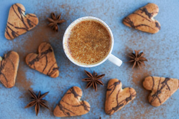 Flatlay of cup of coffee spiced with cinnamon near brown cookies and star anise
