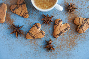 Flatlay of cup of coffee spiced with cinnamon near brown cookies and star anise