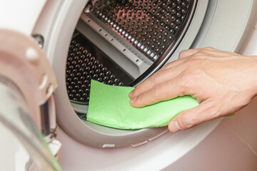 Hand cleaning moisture from the washing machine drum. Washing machine maintenance concept
