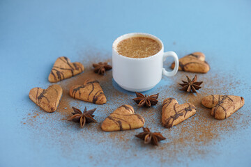 Fototapeta na wymiar White cup of coffee spiced with cinnamon near brown cookies and star anise