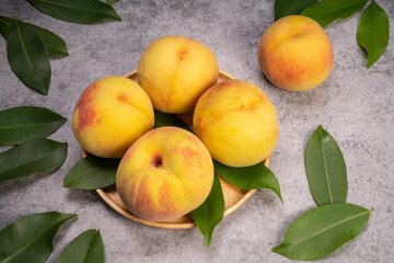 Golden Yellow Peach in wooden plate on gray background.