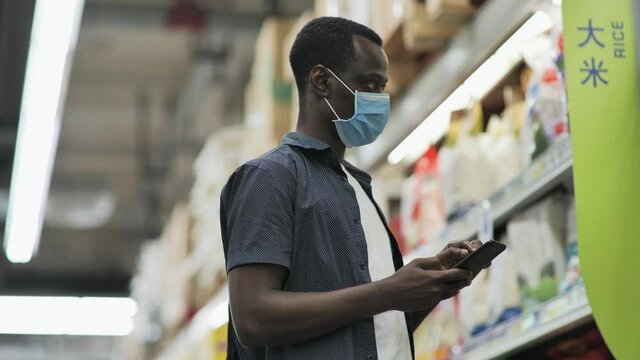 Black man wear mask holding a phone in the shop