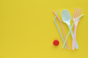 Disposable plastic tableware on yellow background.