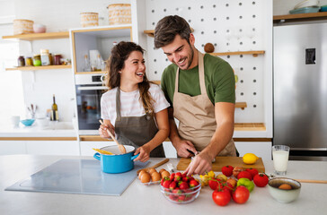 Happy young couple preparing food in kitchen at home