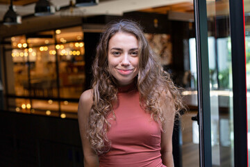 European girl with dark and curly hair with lights behind