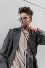 Portrait of handsome guy model with hairstyle and stubble in fashion look clothes with sunglasses...