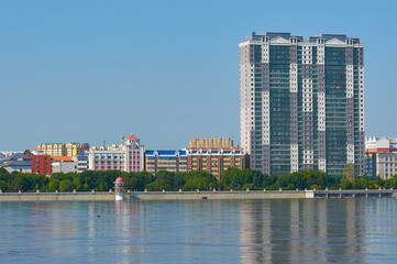 Sunny view of the embankment of the city of Heihe, China from the city of Blagoveshchensk, Heihe. Reflections of buildings in the Amur river. The period of danger of flooding.