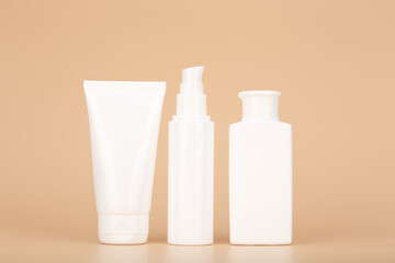 Set of white unbranded cosmetic tubes for face and body care in a row against pastel beige background. Concept of organic, natural, eco friendly cosmetics and beauty products for daily skin care