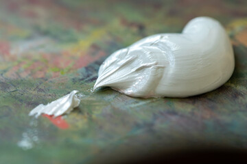 White oil paint on a palette. Extruded white paint on a professional multicolor palette. Stroke...