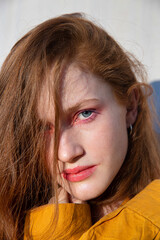 Serious portrait girl with bright makeup near the wall