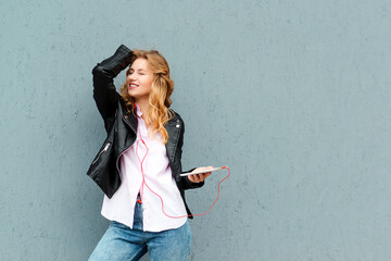 Woman listening music with headphones and gadget. Girl dancing, enjoying freedom and music.