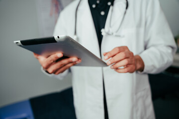 Mixed race male nurse standing in office holding digital tablet