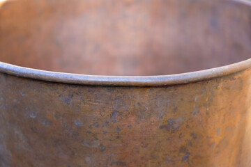 Fototapeta premium The edge of the copper pot, diverging upwards. Handmade. Copy space.