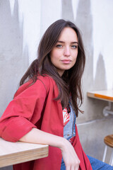 White european young girl with big lips with wall behind at a table