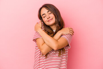 Young caucasian woman isolated on pink background hugs, smiling carefree and happy.
