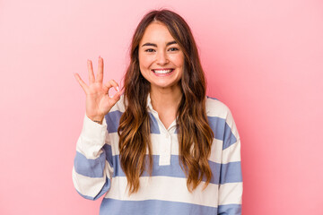 Young caucasian woman isolated on pink background cheerful and confident showing ok gesture.