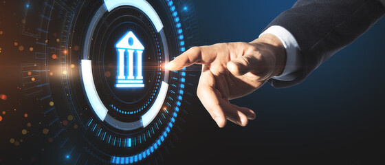 Businessman hand pointing at creative glowing blue public building hologram on dark background....
