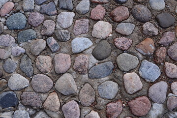 Texture. The sidewalk is lined with granite stones of various shapes and colors. 