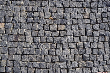 Texture. The sidewalk is lined with small gray granite stones.
