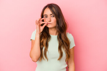 Fototapeta premium Young caucasian woman isolated on pink background with fingers on lips keeping a secret.