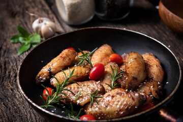 Baked chicken wings served with different sauces in a pan. Black background
