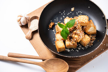 Fried tofu with sesame seeds and fried Garlic spices  in a pan on white background. concept asian and vegetarian cooking.