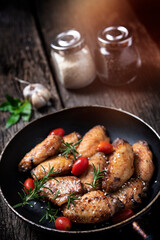 Baked chicken wings served with different sauces in a pan. Black background