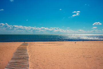 Seascape on a sunny day. Wooden pathway on the beach