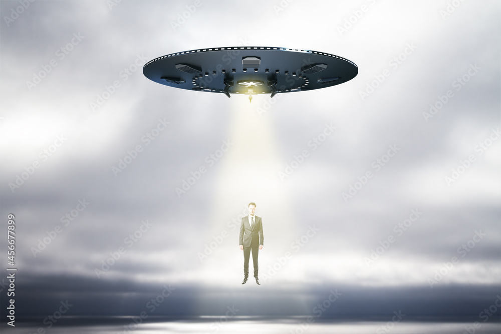 Aufkleber Abstract UFO with light taking businessman on sky background with mock up place. Spaceship, technology and mystery concept.