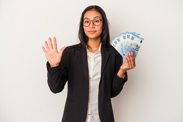 Young business latin woman holding bills coffee isolated on white background  smiling cheerful showing number five with fingers.