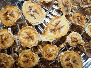 dried banana slices are lying on the pallet of an electric dryer. cooking banana chips
