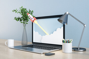 Close up of creative blue designer workspace with abstract rocket on laptop screen, coffee cup, decorative plant, lamp and supplies. Start up and workplace concept. 3D Rendering.