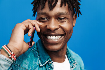 african man calling on the phone on blue background, 5g internet concept, high speed internet on phone