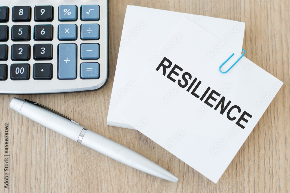 Poster white note card with the text resilience on the table next to the calculator and pen