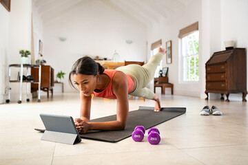 Mixed race woman doing plank and watching online lesson