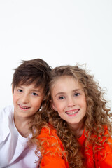 curly girl in an orange long sleeve t-shirt sits next to her friend in a white t-shirt