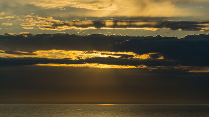 Beautiful sea landscape with sunset on the horizon. Sochi, Black Sea coast of south of Russia. Scenic sky with clouds over the golden water of Black sea. Luxury clouds and natural sky background