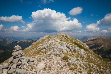 A pile of stones (also called cairn, Steinmännchen or Steinmandl) in the peak of Italian apennines with blue sky, peak of mount Sassetelli, Lazio