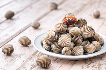 fresh steamed cockles, boiled cockles in ceramic plate on old white wood texture background, easy seafood recipe menu, blood cockle