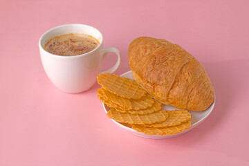 Salty waffles and sweet croissant with a cup of frothy coffee