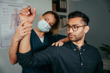Caucasian female nurse adjusting arm of male patient in clinic