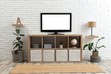 Modern TV set near white brick wall in living room