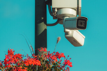 CCTV security cameras at town square post decorated with some flowers