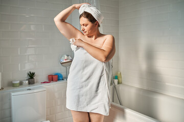 Woman taking care of underarms and wipes her body while having beauty procedures