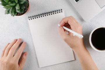 Womans hands writing to do list or plans in notebook on office desk. Top view, copy space