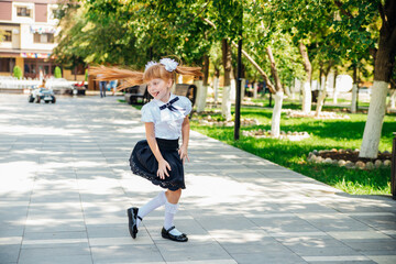 A little girl elementary school student is having fun walking down the street.The child happily goes to school.