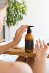 Woman's holding botles with spa cosmetics in bathroom. Beauty blogger, salon therapy, minimalism concept, copyspace
